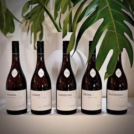 Bouteilles de thés Grands Jardins aux étiquettes épurées, présentées comme des crus dans un décor végétal.